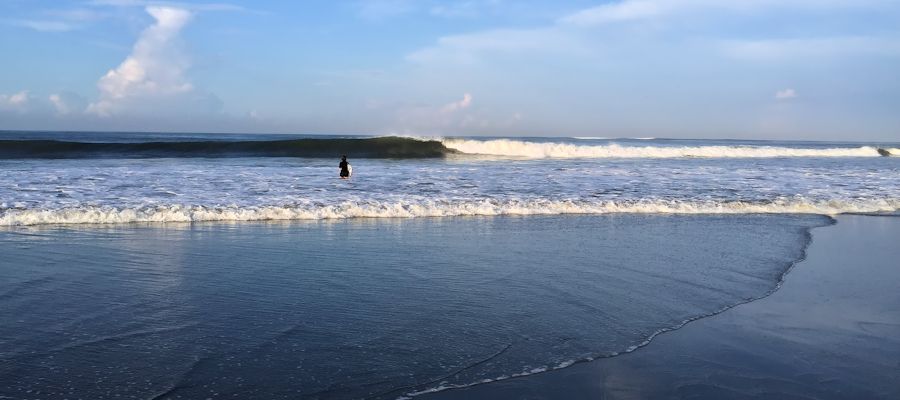 Surfer in Canggu going to water with her surfboard.